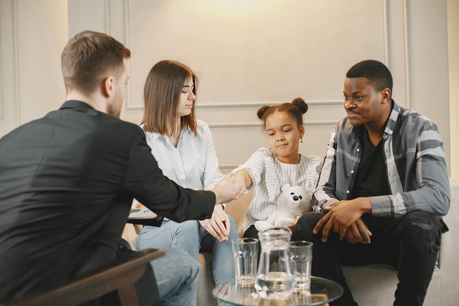 A family in a thoughtful counselling session with a professional in a modern setting.